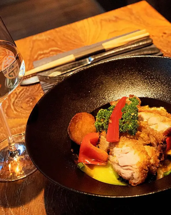 Crispy chicken with vegetables in a black bowl